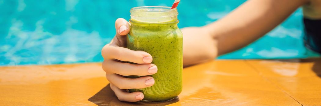 Woman with a green smoothies of spinach and banana on the background of the pool. Healthy food, healthy smoothies. BANNER, LONG FORMAT