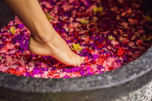 Attractive Young woman in bath with petals of tropical flowers and aroma oils. Spa treatments for skin rejuvenation. Alluring woman in Spa salon. Girl relaxing in bathtub with flower petals. Luxury.