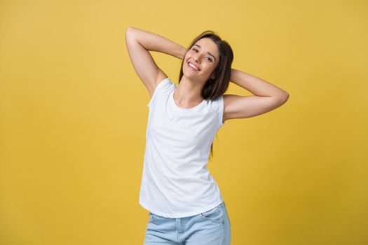 Close-up portrait of cute young woman relaxing with hand behind head. Isolated over yellow background