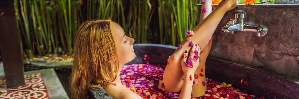 Attractive Young woman in bath with petals of tropical flowers and aroma oils. Spa treatments for skin rejuvenation. Alluring woman in Spa salon. Girl relaxing in bathtub with flower petals. Luxury. BANNER, LONG FORMAT