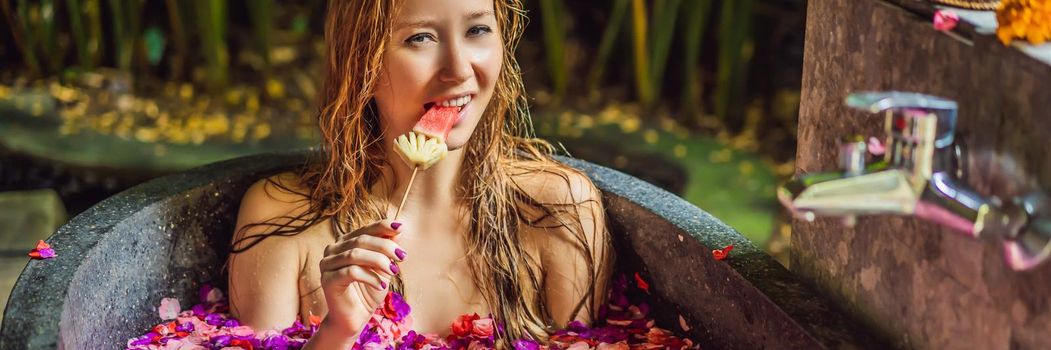 Attractive Young woman in bath with petals of tropical flowers and aroma oils. Spa treatments for skin rejuvenation. Alluring woman in Spa salon. Girl relaxing in bathtub with flower petals. Luxury. BANNER, LONG FORMAT