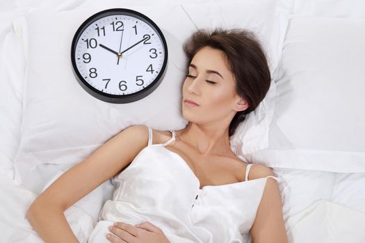 Happy woman waking up and turning off the alarm clock