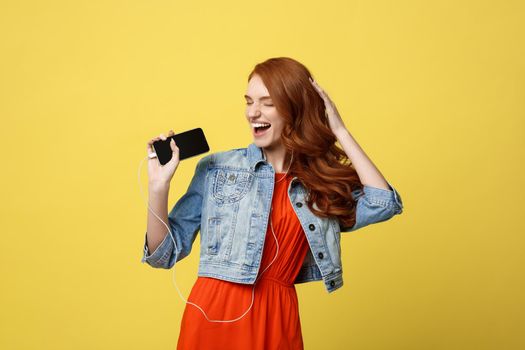 Lifestyle Concept: Young beautiful woman with headphones dancing isolated on bright yellow background
