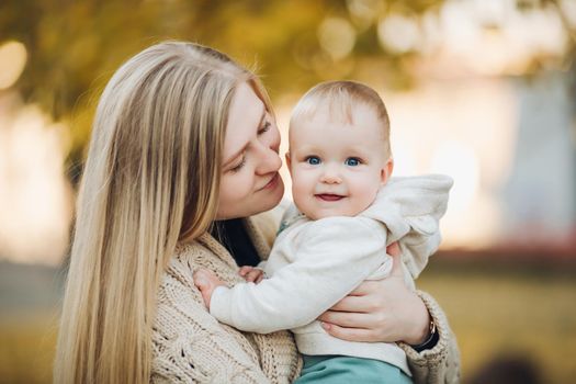 Beautiful mother and daughter walking in the park in autumn, portrait. Mom and daughter, family concept. A little girl in her mother's arms.