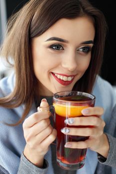 young woman holding a cup of hot mint tea or hot lemonade