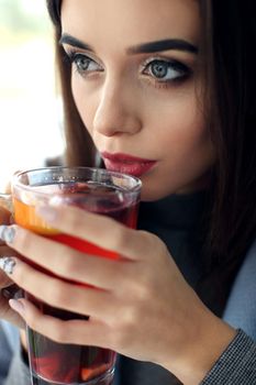 young woman holding a cup of hot mint tea or hot lemonade