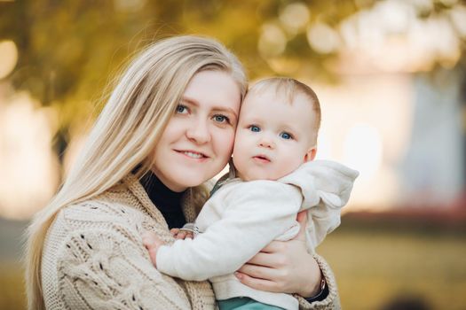 Beautiful mother and daughter walking in the park in autumn, portrait. Mom and daughter, family concept. A little girl in her mother's arms.