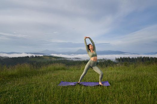 Pretty young woman with athletic body shape spending morning time for yoga practice on fresh air. Harmony, relaxation and spirituality concept.