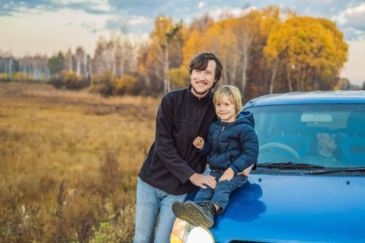 Dad and son are resting on the side of the road on a road trip. Road trip with children concept.