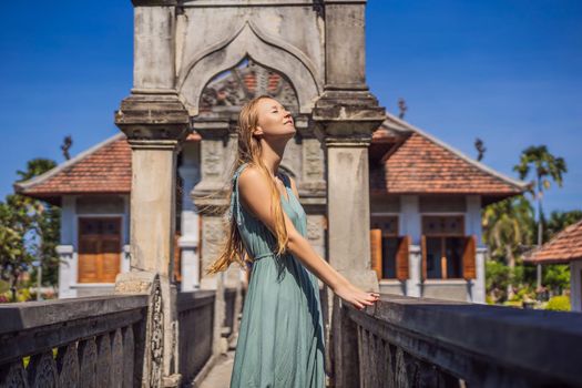 Young woman in dress in Water Palace Soekasada Taman Ujung Ruins on Bali Island in Indonesia. Amazing old architecture. Travel and holidays background.