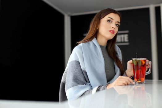 young woman holding a cup of hot mint tea or hot lemonade