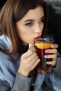 young woman holding a cup of hot mint tea or hot lemonade