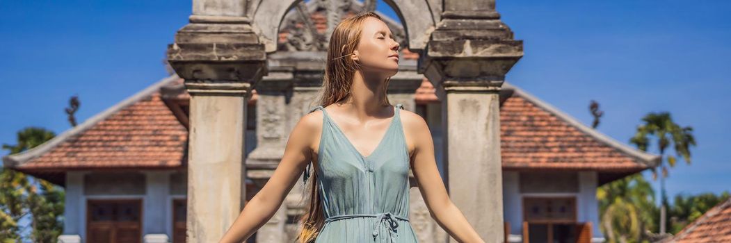 Young woman in dress in Water Palace Soekasada Taman Ujung Ruins on Bali Island in Indonesia. Amazing old architecture. Travel and holidays background. BANNER, LONG FORMAT