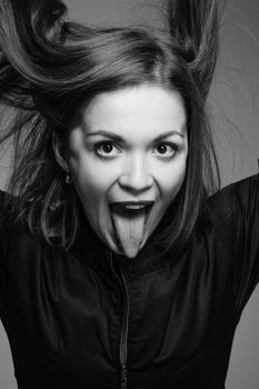 Girl shows the tongue with her mouth open and picks up hair depicts beast. Studio black and white portrait of a woman.