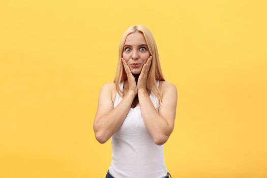 Young blonde girl with a surprised look on yellow background. Picture including copy space for text.