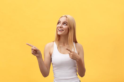 Woman showing pointing on yellow background. Very fresh and energetic beautiful young girl smiling happy presenting on yellow background