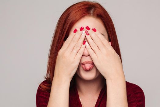 Beautiful young lady with closed eyes holding her hand near head. Clouse up of pretty red haired woman in bordo blouse with headache. Sadly girl touching her hair by hand and thinking about problem.