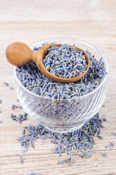 A bowl of dried lavender flower on wooden table.