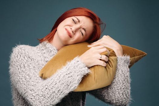Ill and tired woman having terrible headache. Beautiful model holding one hand on forehead and with another hand holding brown pillow on shoulder. Concept of illness and advertisement.