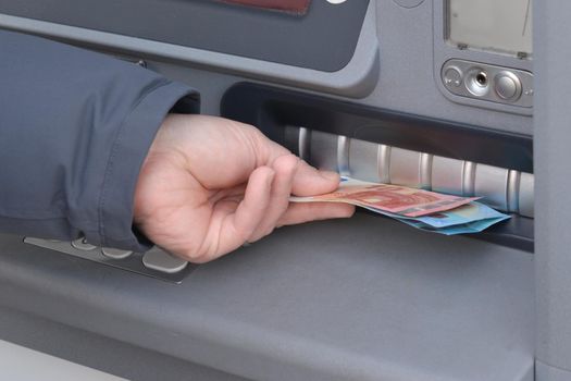 Close-up of hand of man to withdraw money from an ATM