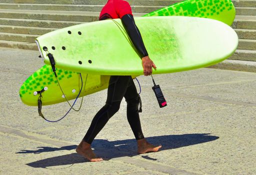 Surfer in wet suit after training and in hands holds surfboards. Teacher in a serf school