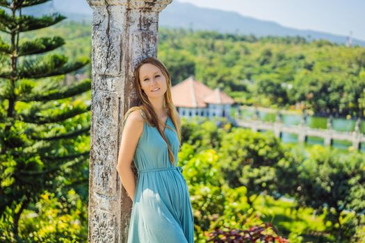 Young woman in dress in Water Palace Soekasada Taman Ujung Ruins on Bali Island in Indonesia. Amazing old architecture. Travel and holidays background.