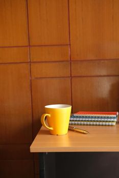 yellow color mug mockup with with notebooks on table .