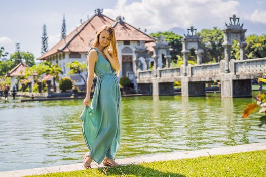 Young woman in dress in Water Palace Soekasada Taman Ujung Ruins on Bali Island in Indonesia. Amazing old architecture. Travel and holidays background.