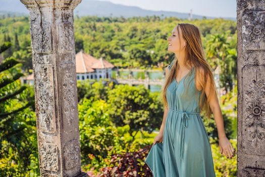 Young woman in dress in Water Palace Soekasada Taman Ujung Ruins on Bali Island in Indonesia. Amazing old architecture. Travel and holidays background.