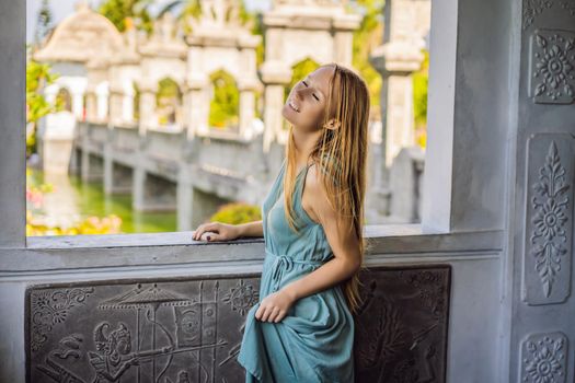 Young woman in dress in Water Palace Soekasada Taman Ujung Ruins on Bali Island in Indonesia. Amazing old architecture. Travel and holidays background.