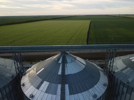 Grain elevator. Metal grain elevator in agricultural zone. Agriculture storage for harvest. Grain silos on green nature background. Exterior of agricultural factory
