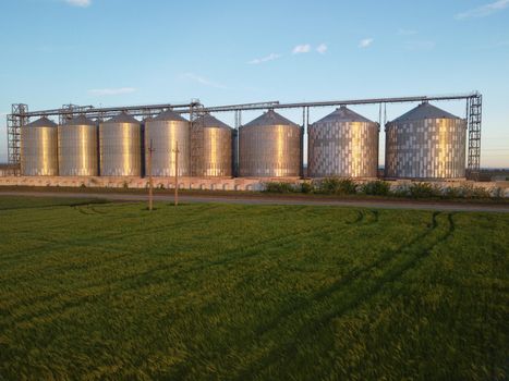 Grain elevator. Metal grain elevator in agricultural zone. Agriculture storage for harvest. Grain silos on green nature background. Exterior of agricultural factory
