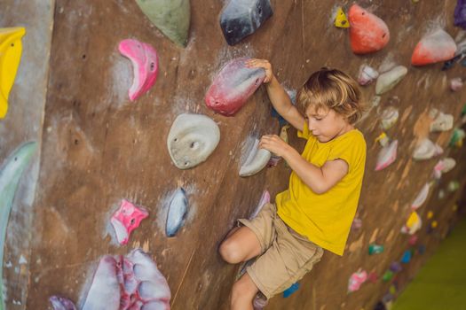 little boy climbing a rock wall in special boots. indoor.