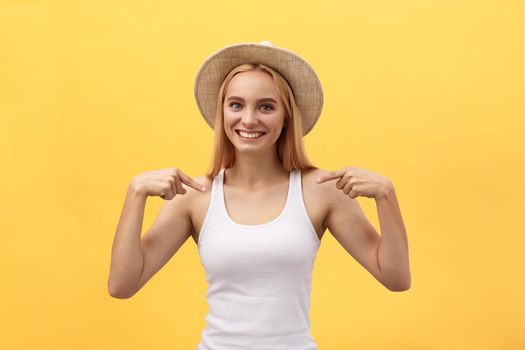 Clothing, design and advertising concept. Indoor shot of positive friendly young female pointing at copy space on her blank white t-shirt for your text or promotional content.