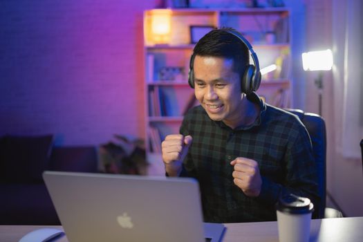 Asian influencer man smile youtuber live streaming or working conferrence with laptop and wearing headphone. Asian man teaching online.