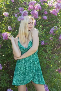 Fashionable girl model near a lilac bush. Spring flowers and beautiful blonde woman. Model appearance. Soft focus