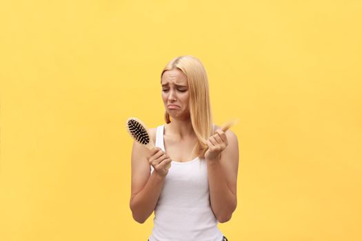Sad girl looking at her damaged hair with comb in hand.