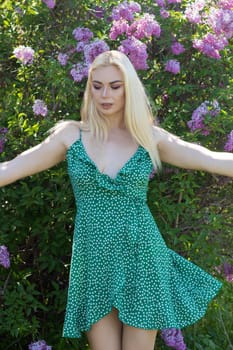 Fashionable girl model near a lilac bush. Spring flowers and beautiful blonde woman. Model appearance. Soft focus