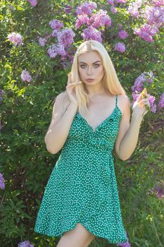 Fashionable girl model near a lilac bush. Spring flowers and beautiful blonde woman. Model appearance. Soft focus