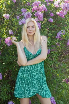 Fashionable girl model near a lilac bush. Spring flowers and beautiful blonde woman. Model appearance. Soft focus