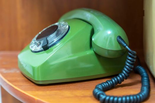 green vintage phone with a rotating dial dial. the phone with the receiver on the shelf