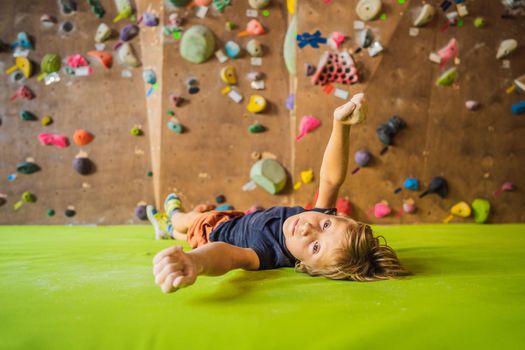 Boy resting after climbing a rock wall indoor.