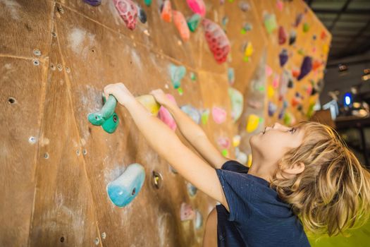 little boy climbing a rock wall in special boots. indoor.