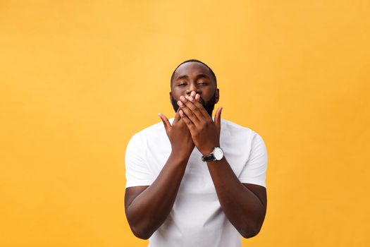 Portrait of african american man with hands raised in shock and disbelief. Isolated over yellow background