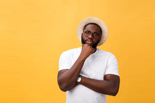 Portrait of a pensive afro american man in glasses looking up at copyspace isolated on a yellow background.