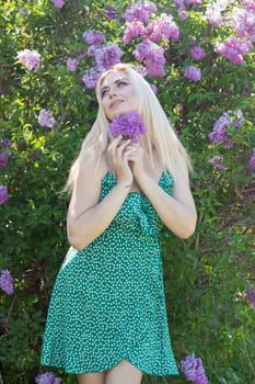 Fashionable girl model near a lilac bush. Spring flowers and beautiful blonde woman. Model appearance. Soft focus