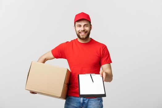 Delivery Concept: Young handsome delivery man with paper boxes giving you a document to sign.