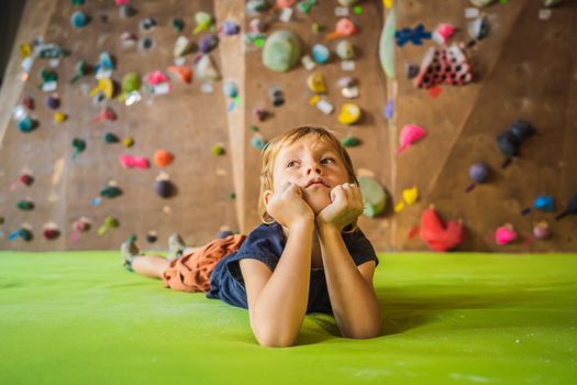 Boy resting after climbing a rock wall indoor.