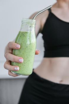 Young millenial blond woman drinking vegan smoothie drink detox. Woman doing yoga exercises at home. Clean eating, weight loss, healthy dieting food concept. Stay healthy. Wellness