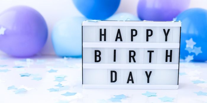 Lightbox with text HAPPY BIRTHDAY on Abstract defocused blurred festive background for holiday. Blue ballons and confetti. Greeting card. Boy concept